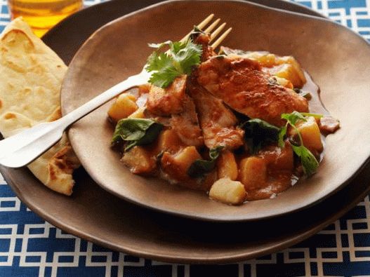 Photo de poulet à la sauce tomate au curry avec pommes de terre et épinards