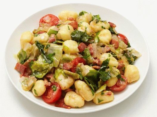 Photo de gnocchi frits avec du bacon et une salade d'escariol