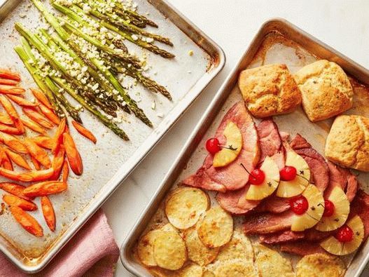 Dîner de Pâques avec jambon, légumes et un pain sur deux plaques à pâtisserie